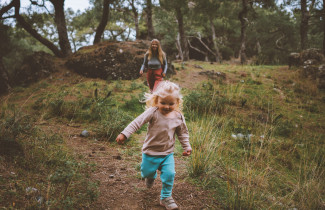Aikuinen ja lapsi juoksevat metsässä.