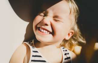 Lapsi hymyilee auringossa.