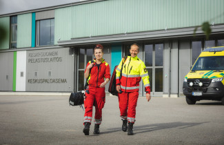 Pelastustoimen ammattilaiset kävelevät Keski-Suomen pelastusaseman edessä, kuvassa myös ambulanssi.