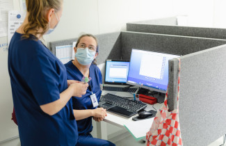 Kaksi sairaanhoitajaa keskustelevat tietokoneen ääressä.