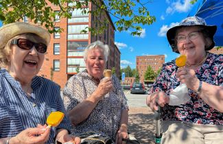 Kolme naista kesällä ulkona syömässä jäätelöä