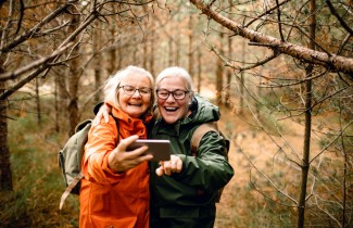 Kaksi henkilöä metsässä ottamassa selfietä.