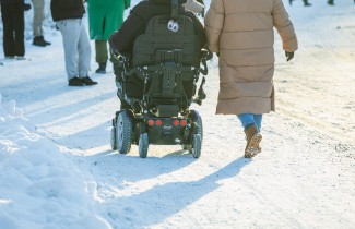 Pyörätuolia käyttävä henkilö ulkoilemassa kävelevän henkilön kanssa