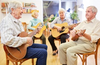 Neljä ikääntynyttä ihmistä soittaa kitaraa.