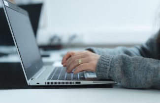 Henkilö kirjoittaa kannettavalla tietokoneella.