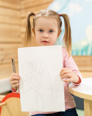 Pieni tyttö näyttää omaa piirustustaan.