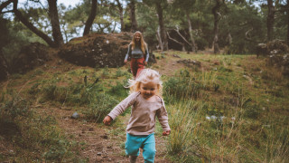 Aikuinen ja lapsi juoksevat metsässä.
