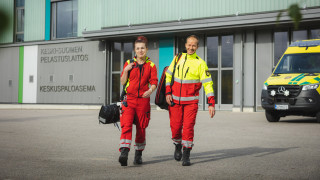 Pelastustoimen ammattilaiset kävelevät Keski-Suomen pelastusaseman edessä, kuvassa myös ambulanssi.