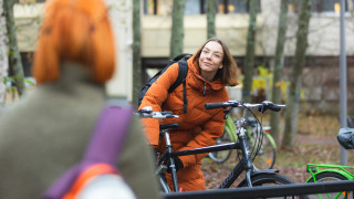 Nainen saapuu pyörällä tapaamaan ystäväänsä.