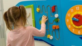 Lapsi leikkii seinällä olevalla värikkäällä aktiivitaululla. 