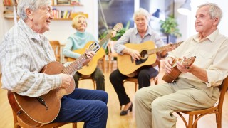 Neljä ikääntynyttä ihmistä soittaa kitaraa.